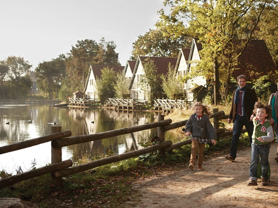 Gezin wandelt over een pad langs het water in de bosrijke omgeving van Vakantiepark Efteling Bosrijk.