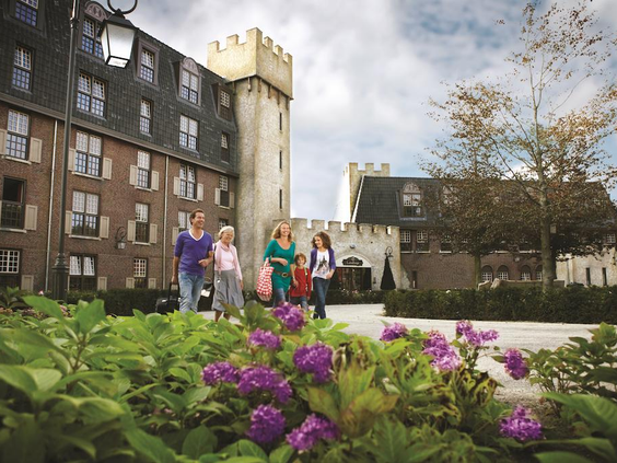 Gezinnen wandelen over het gezellige dorpsplein van Efteling Bosrijk met de appartementen in het Poorthuys.