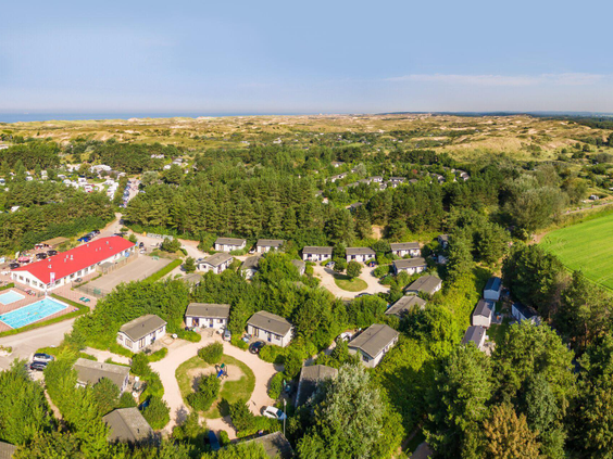 Luchtfoto van Roompot Vakantiepark Egmond aan Zee, met de chalets gelegen in een groene omgeving vlakbij het uitgestrekte duingebied van Noord-Holland.