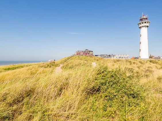 De historische witte vuurtoren J.C.J. van Speijk, die trots bovenop een hoge duin uitkijkt over Egmond aan Zee en de Noordzee.