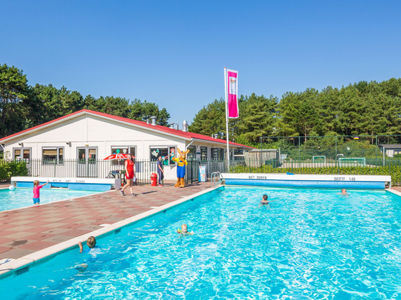 Kinderen en ouders genieten van het zonnige, verwarmde buitenzwembad op Roompot Vakantiepark Egmond aan Zee.