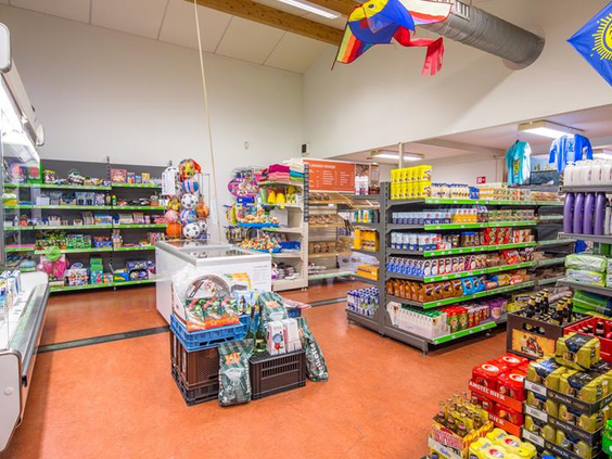 De goed gesorteerde parksupermarkt op Vakantiepark Egmond aan Zee, met schappen vol boodschappen, drinken, speelgoed en strandartikelen.