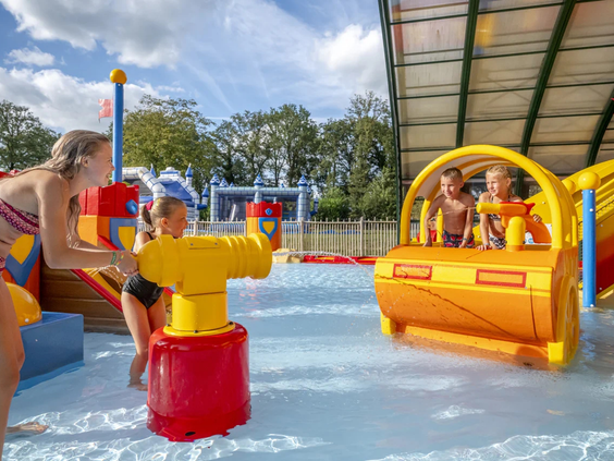 Een kind speelt bij de interactieve wateremmer in het binnenzwembad
