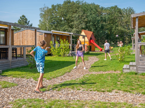 Kinderen rennen vrolijk over de grasvelden tussen de chalets door