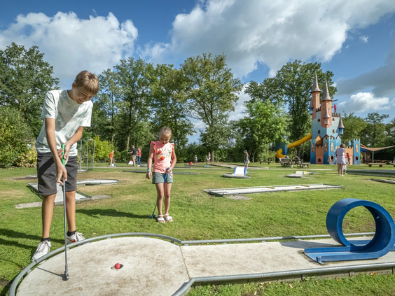 Meisje slaat een balletje op de midgetgolfbaan van de camping