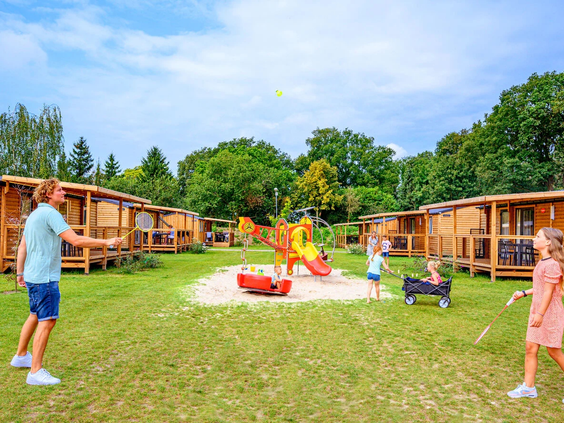 Moderne chalets en lodges gelegen aan een groen speelveld op de camping in Gelderland