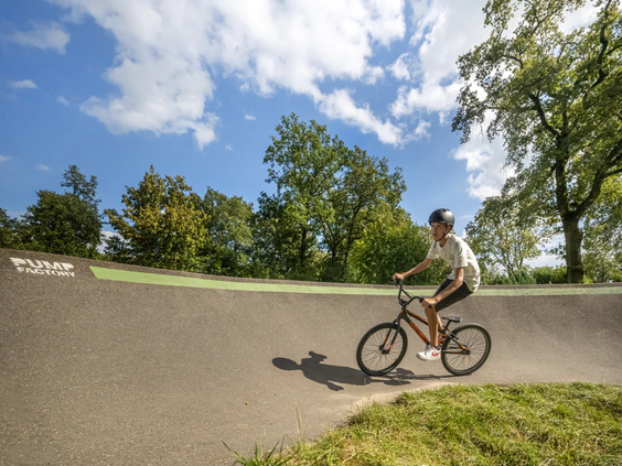 Kind fietst over de golvende pumptrack baan van de camping