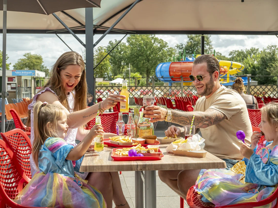 Een gezin geniet van een maaltijd op het terras van het parkrestaurant