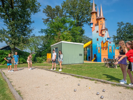 Kinderen spelen in de grote zandbak bij een houten speelkasteel
