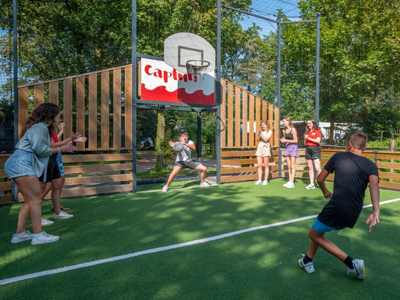 Jongeren spelen voetbal op het omheinde multisportveld van het park