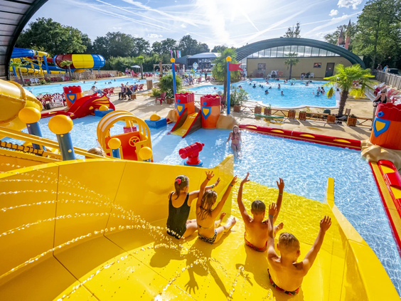 Kinderen roetsjen van de brede gele waterglijbaan in het zwembad