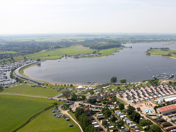 Weids uitzicht over de recreatieplas en het groene landschap van de Betuwe rondom Vakantiepark Eiland van Maurik.