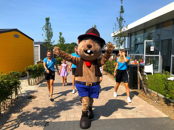 De bever-mascotte van Vakantiepark Eiland van Maurik loopt voorop in een polonaise met het animatieteam en kinderen.