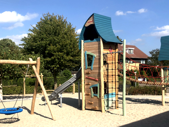 Een houten speeltuin met een klimtoren, glijbaan, schommel en touwbrug op Vakantiepark Eiland van Maurik.