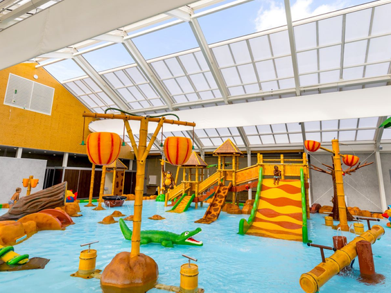 Het overdekte waterspraypark op Vakantiepark Eiland van Maurik vol met kleurrijke speeltoestellen, glijbanen en waterkanonnen.