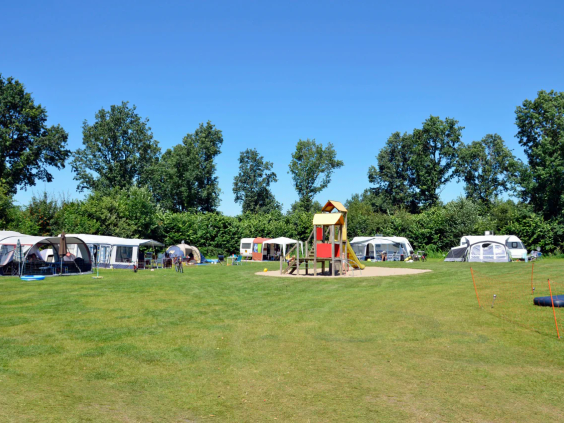 Caravans en tenten op de groene grasvelden van de camping in Zeewolde
