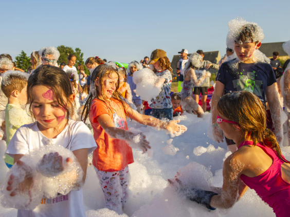 Kinderen vieren feest tijdens een grote schuimparty op de camping