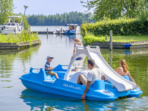 Blauwe waterfietsen met een glijbaan liggen in het water bij het strand