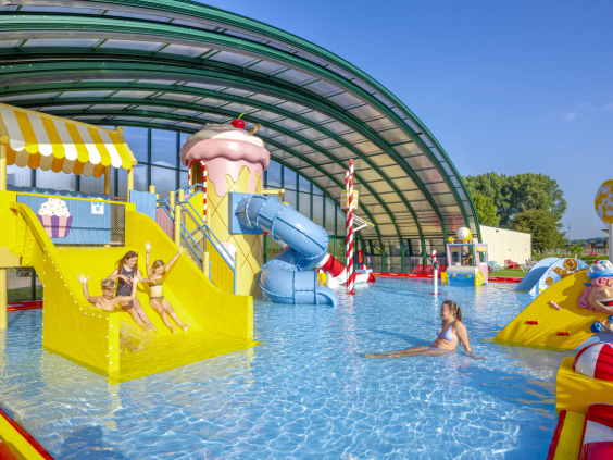 Het lichte binnenzwembad met glijbanen en waterspeelelementen