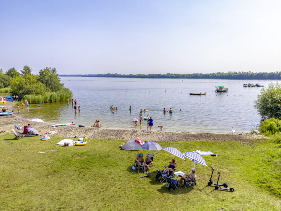 Zicht op het lange zandstrand en het water van het Nuldernauw bij de camping