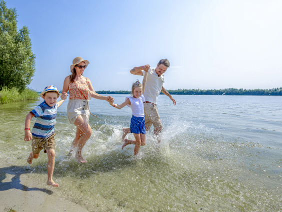 Een gezin rent vrolijk het ondiepe water van het strand in