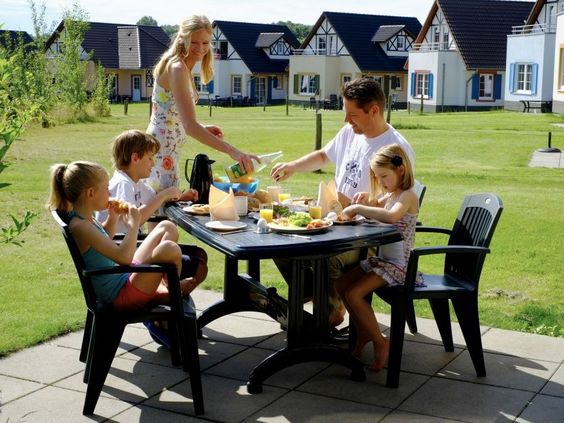 Een gezin eet en drinkt gezellig samen aan een tafel op het terras van hun vakantiehuis op Ferienresort Cochem.
