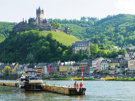 Uitzicht vanaf het water op het stadje Cochem en het sprookjesachtige kasteel de Reichsburg dat hoog boven de rivier de Moezel uittorent.