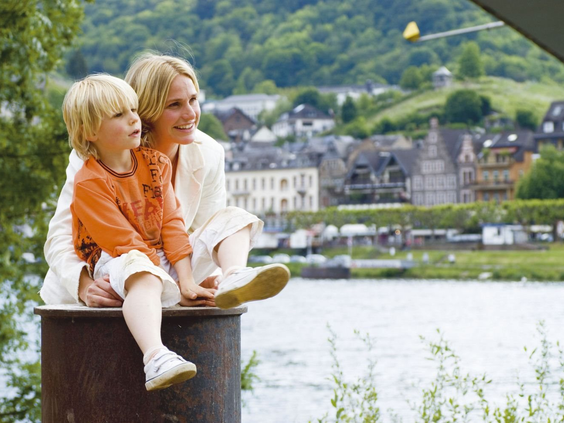 Een moeder en haar zoon genieten samen van het uitzicht over de rivier de Moezel en het stadje Cochem.