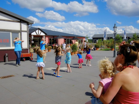 Een groep kinderen danst buiten vrolijk mee met de dansjes van het animatieteam tijdens de kinderdisco op Ferienresort Cochem.