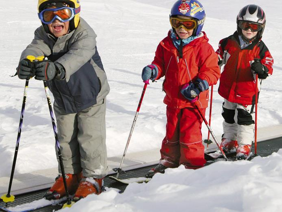 Kinderen in rode skipakken krijgen skiles op een besneeuwde piste en leren de basis van het skiën in de Harz.