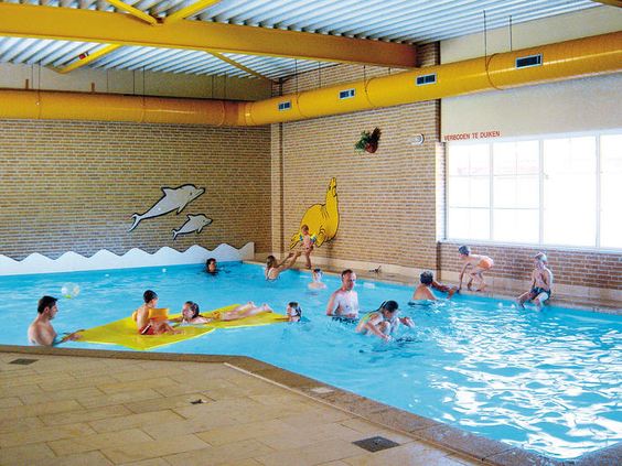 Kinderen en gezinnen zwemmen en spelen in het overdekte binnenzwembad van Vakantiepark Hellendoorn.