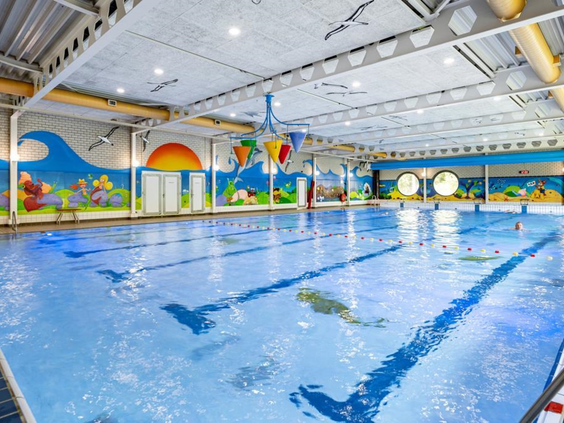 Het ruime binnenzwembad van Vakantiepark Hunzedal, met vrolijke wanddecoraties en ruimte om te zwemmen en te spelen voor het hele gezin.