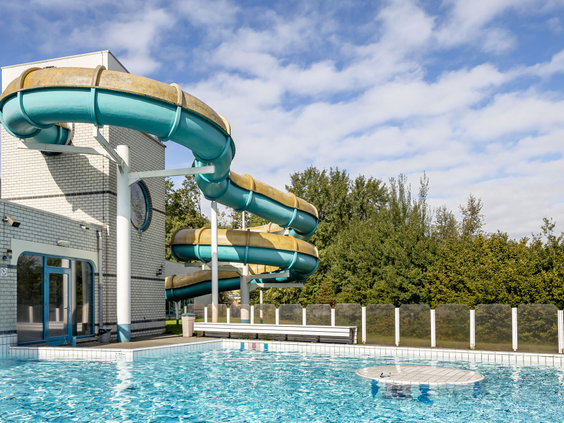 Spannende waterglijbaan die uitkomt in het buitenzwembad van Vakantiepark Hunzedal, de perfecte plek voor waterpret op een zonnige dag.