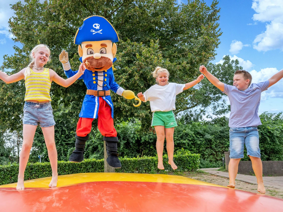 Kinderen springen samen met een mascotte op de grote airtrampoline