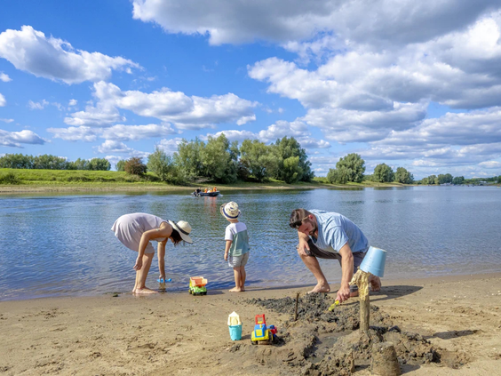 Kinderen bouwen zandkastelen op het strand aan de oever van de rivier