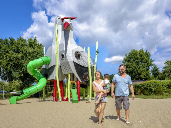 Kinderen spelen bij een groot speeltoestel in de vorm van een raket op het park