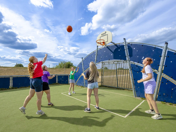 Jongeren spelen een potje voetbal op het omheinde multisportveld