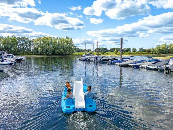 Een gezin op een witte waterfiets in de jachthaven bij de IJssel
