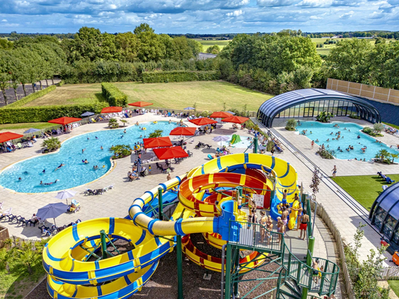 Overzicht van het waterpark met diverse glijbanen en het buitenzwembad op de camping