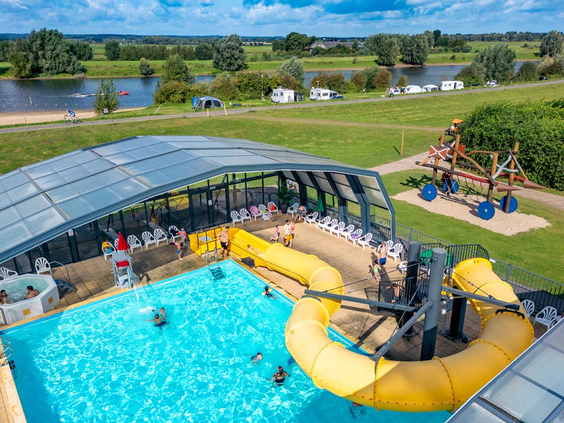 Het zwembad van IJsselstrand met een gele glijbaan en een uitschuifbare overkapping