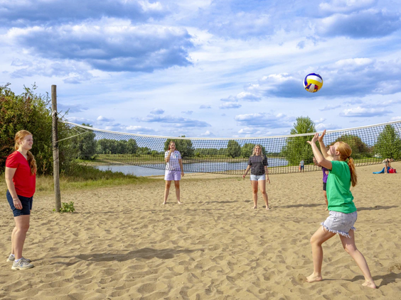 Meisjes spelen beachvolleybal op het zandveld aan de rivier