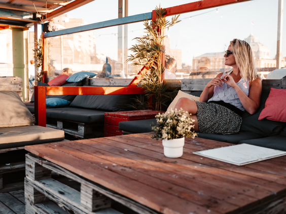 Een vrouw ontspant op een comfortabele loungebank op het zonnige terras van Vakantiepark Kijkduin.