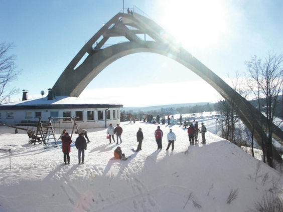 Wintersporters en families genieten van de sneeuw bij de Erlebnisberg Kappe met de Panorama Erlebnis Brücke in Winterberg.