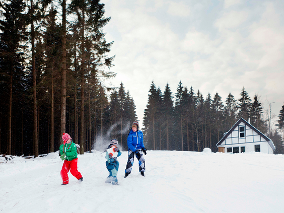 Drie kinderen oefenen met skiën op een rustige, besneeuwde piste omringd door dennenbomen in Winterberg.