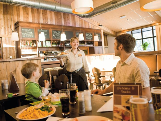 Een gezin met een jong kind bestelt eten in het gezellige restaurant van Landal Winterberg.