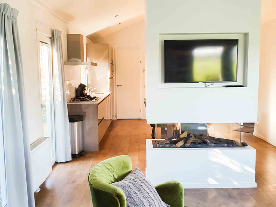 Een modern chalet-interieur op Vakantiepark Leuvert met een comfortabele zithoek rondom een sfeervolle elektrische haard.