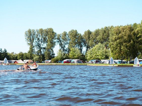 Mensen varen en waterfietsen op het grote recreatiemeer van Vakantiepark Marina Beach in Zeeland.