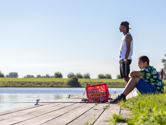 Kinderen zitten te vissen aan de rand van een houten steiger bij het water op Vakantiepark Marina Beach.