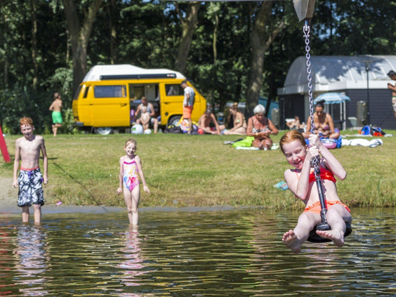 Kinderen spelen in het water en op het strandje van de recreatieplas bij Vakantiepark Marina Beach op een zonnige dag.