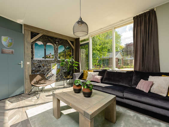 De sfeervolle woonkamer van een Reggehooiberg op Vakantiepark Molke, met een grote hoekbank en uitzicht naar buiten.